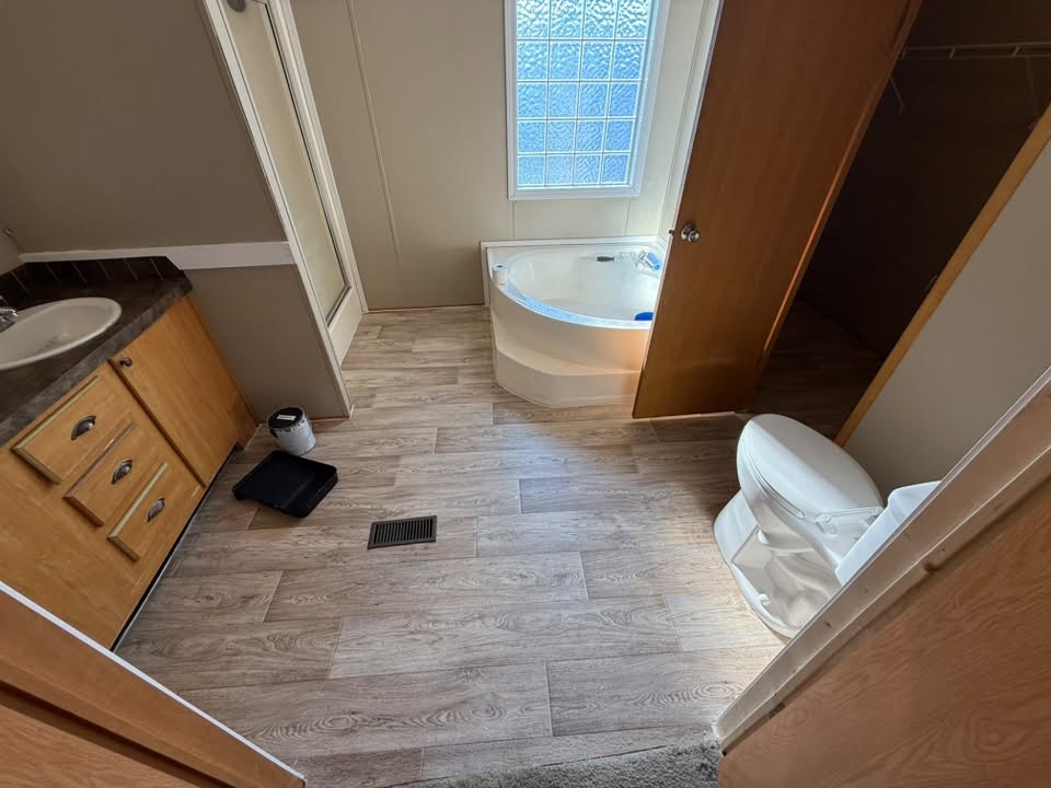 Bathroom remodel with a corner tub, wood vanity, and new wood-look flooring